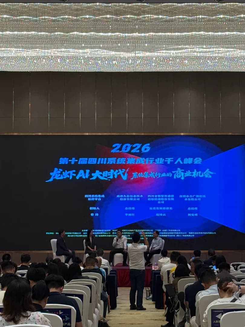 2026 四川系统集成行业千人峰会主席台多人论坛圆桌讨论现场,多位行业嘉宾并排就座、手持话筒交流 AI Agent 趋势,背景为峰会舞台主视觉