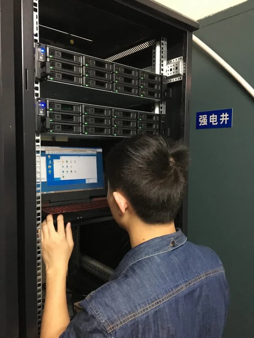元禾大千艺术品有限公司机房实施照片,工程师在机柜前调试群晖 NAS 主备存储设备,多台机架式 NAS 硬盘指示灯正常运行,体现企业文件中心部署与现场实施交付